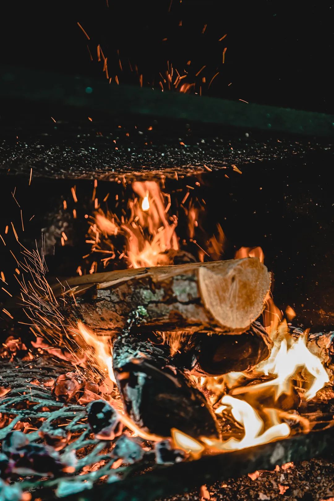 Kokopuu palaa kirkkaissa liekeissä nuotion sisällä pimeässä ympäristössä.